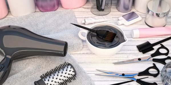 Hair cutting shears, combs, hair dye and professional cosmetics for hair located on a wooden table.